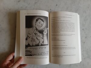 An open spread of two pages, with an illustration of Sherlock Holmes writing a letter on the left page, and text from the short story A Correspondence on the right hand page. 